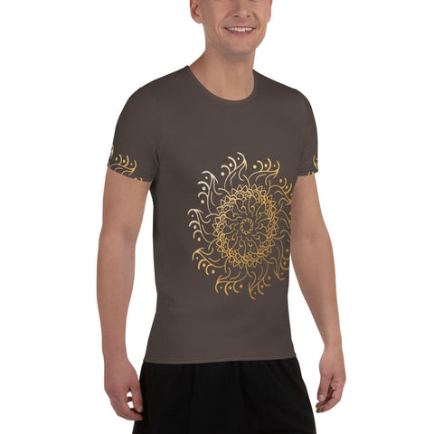 Wearing a dark brown Magick "Guruuu" Men's Athletic T-shirt with a large gold mandala design, this person exudes style and performance. They smile in black pants, benefiting from moisture management technology against a plain white background.