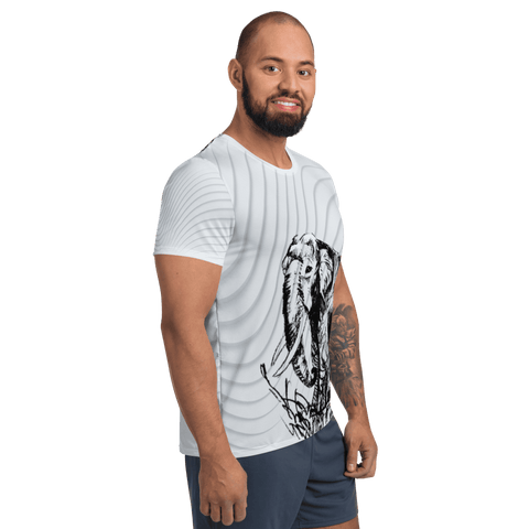 A man with a beard smiles while standing sideways in magickwear's "A Giant" Men's Athletic T-shirt, showcasing an elephant design and crafted from MaxDri moisture management fabric. He pairs it with dark shorts, his tattooed arm and the plain black background enhancing his relaxed vibe.