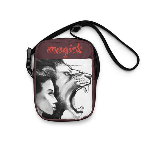 The "Courage" Utility Crossbody Bag by Magick is a compact brown bag with adjustable black straps, showcasing a design that includes a woman's face next to a roaring lion. It features the word "Magick" in red cursive at the top and is crafted to be water-resistant for enhanced durability.