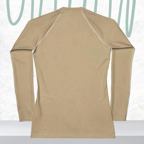 The "Heroine" Women's Rash Guard by Magick, featuring long sleeves and UPF 50+ protection in beige, is shown from the back against a textured white background with teal abstract lines above it.