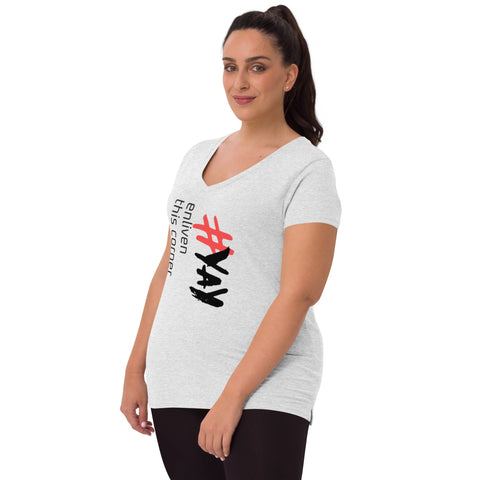 A woman with a ponytail is wearing the "Enliven" Women’s V-neck T-shirt by Magick in light gray. This eco-friendly tee, crafted from recycled fabric, features bold black and red "#YAY" lettering, along with smaller text that says "enliven this corner." She stands against a plain background.