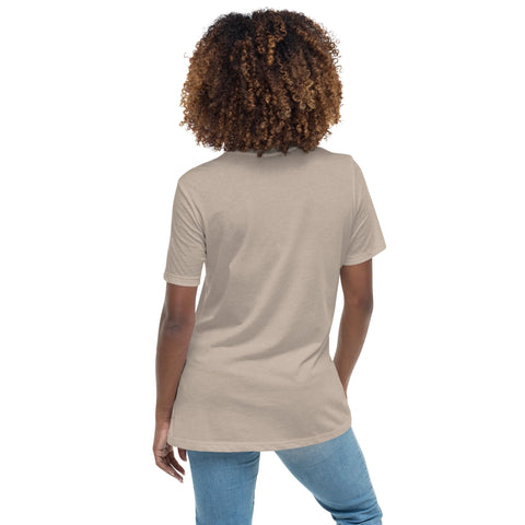 A person with curly hair in a beige "Shine Forth" Women's Relaxed T-Shirt by Magick, crafted from 100% combed ring-spun cotton for softness and comfort, pairs it effortlessly with blue jeans, standing with their back to the camera.