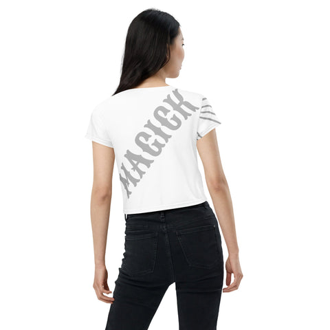 A person with long dark hair is wearing the "Beats" Crop Tee from magickwear, which showcases an eye-catching pattern and the word "MAGICK" in gray across the back. They are paired with black jeans and turned slightly to the side, facing away from the camera.