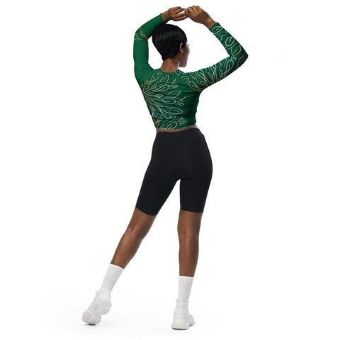 Facing away and stretching arms overhead, they're in a magickwear "Proud of Me" green crop top with white patterns, black cycling shorts, white socks, and sneakers. Ideal for an eco-friendly wardrobe blending style and practicality.