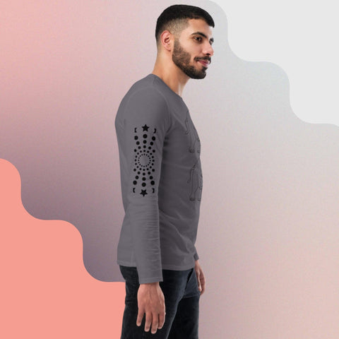 A man with short dark hair and a beard is standing sideways, wearing the "Carry On" unisex fashion long sleeve shirt by magickwear, featuring black star patterns and circular designs on the sleeve. The background has a wavy design with light and dark pink shades blending into light gray.