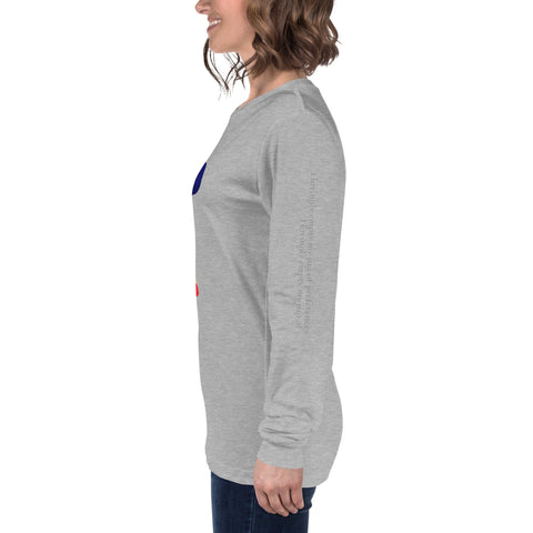 A person with shoulder-length brown hair is wearing a light grey long-sleeve "Renounce" Ladies' Tee by magickwear and dark blue jeans. They are standing in profile, facing left, with a smile on their face. The shirt features colorful graphics on the front and plain sleeves, making it a comfortable and durable addition to any wardrobe.