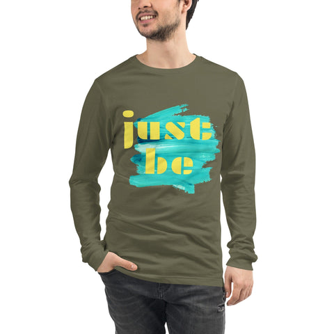 Wearing the "Just Be ..." Unisex Lettering Tee by magickwear, a person stands casually with one hand in their pocket, showcasing its comfortable and durable design. This long-sleeve olive green tee features a bold yellow "just be" atop a turquoise paint stroke.