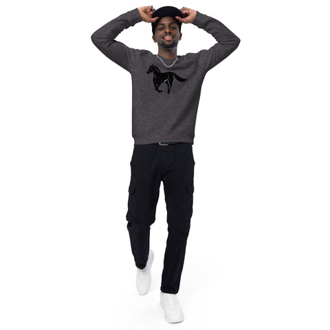 A person is smiling with hands behind their head, wearing a dark gray "A Horse's Kingdom" Unisex Organic Raglan Sweatshirt by magickwear with a black horse graphic, black pants with multiple pockets, and white sneakers. They are also wearing a black cap. The sweatshirt features brushed fleece lining for extra comfort against the plain white background.