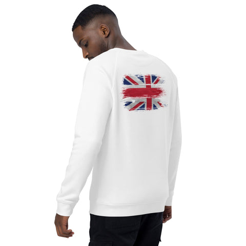 A person is pictured wearing the magickwear "A Horse's Kingdom" Unisex Organic Raglan Sweatshirt, featuring a design similar to the British flag on the back. The cozy, organic cotton sweatshirt is paired with black pants. Standing in profile and gazing downward, they appear lost in a moment of quiet reflection.