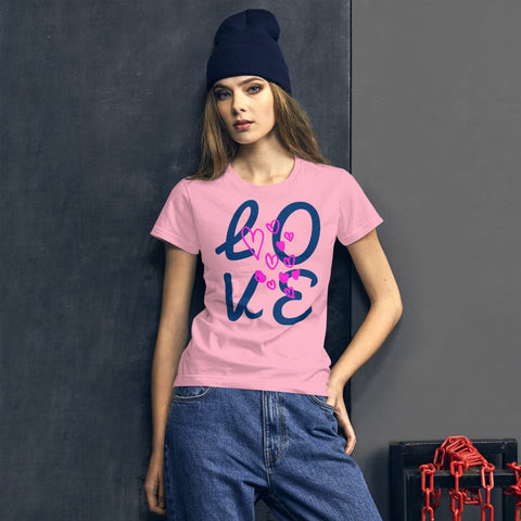A woman wearing a magickwear "LOVE Big" pink 100% cotton t-shirt, classic fit blue jeans, and a black beanie leans against a dark gray wall, with a red chain on the floor beside her.