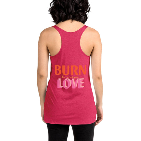 A person with shoulder-length wavy hair is shown from the back, wearing a stylish and comfortable magickwear "Girl Powering" Women's Racerback Tank in pink, featuring the motivational phrase "BURN for what you LOVE" in orange and white text. The person pairs it with black pants, emanating a strong sense of empowerment.